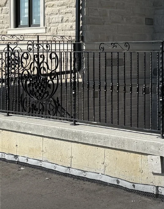 Before: exposed concrete foundation finished with smooth parging under a wrought-iron railing